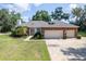 Charming brick home featuring a two-car garage, manicured lawn, and mature landscaping at 1815 Durant Rd, Valrico, FL 33596