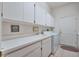 Functional laundry room with white cabinets, countertop, sink and modern appliances at 1815 Durant Rd, Valrico, FL 33596