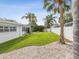 Backyard has tropical plants, gravel ground cover, green grass, a firepit and a fence at 2016 Cove Dr, Largo, FL 33774