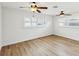 A naturally lit bedroom featuring wood flooring, impact windows, and two ceiling fans at 2016 Cove Dr, Largo, FL 33774
