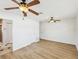 Spacious main bedroom featuring wood floors, impact windows, two ceiling fans, and access to the main bathroom at 2016 Cove Dr, Largo, FL 33774