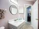 Bright bathroom features a round mirror, modern vanity, and a doorway to the hallway at 2601 Brookville Dr, Valrico, FL 33596