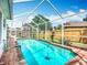 Sparkling screened-in pool area with brick patio, lush landscaping, and clear blue water at 2601 Brookville Dr, Valrico, FL 33596