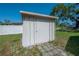 Storage shed with door, stone pathway and green lawn under a sunny blue sky at 3256 Adrian Ave, Largo, FL 33774