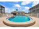 Community pool surrounded by a white fence and lounging furniture for residents at 340 Causeway Blvd # 104, Dunedin, FL 34698