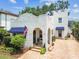 Charming white two-story home featuring a textured exterior, arched entryways, brick pathway and blue awnings at 3405 W Palmira Ave, Tampa, FL 33629