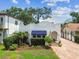 Charming white home boasts a textured exterior, arched entryways, brick pathway, blue awnings, and landscaping at 3405 W Palmira Ave, Tampa, FL 33629