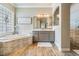 Elegant bathroom featuring a soaking tub with textured tile, modern vanity, and a glass block window at 3656 Kalanchoe Pl, Wesley Chapel, FL 33544