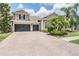 Stately two-story home showcasing a three-car garage, manicured lawn, and lush palm trees for exceptional curb appeal at 3656 Kalanchoe Pl, Wesley Chapel, FL 33544