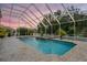 Backyard pool with water features, mature plants, and an enclosed screened enclosure at 3656 Kalanchoe Pl, Wesley Chapel, FL 33544