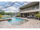Backyard pool with water features, mature plants, and a screened enclosure with attached balcony at 3656 Kalanchoe Pl, Wesley Chapel, FL 33544