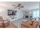 Cozy living room with a brick fireplace, ceiling fan, and a large flat-screen television at 3968 Orchard Hill Cir, Palm Harbor, FL 34684