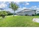 Charming home showcasing a lush green lawn, complemented by a tree, landscaping and gray exterior paint at 4041 Star Island Dr, Holiday, FL 34691