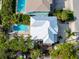 Aerial shot of a home with a white metal roof, pool, mature trees, and a long driveway in a sunny neighborhood at 405 8Th N Ave, Tierra Verde, FL 33715