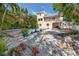 The spacious backyard features a pool, white gravel, tropical landscaping, and a stairway to a second story balcony at 405 8Th N Ave, Tierra Verde, FL 33715