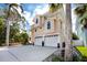 Charming two-story home with a two-car garage, a long driveway, and lovely landscaping, including palm trees and potted plants at 405 8Th N Ave, Tierra Verde, FL 33715
