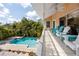 Beautiful covered pool deck with turquoise outdoor furniture overlooks a pristine pool and lush tropical landscaping at 405 8Th N Ave, Tierra Verde, FL 33715