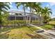 A charming view of the backyard with lush green grass, decorative trees, and a screened lanai provides serene outdoor space at 4210 Palm Dr, Punta Gorda, FL 33950