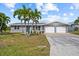 Charming single-story home featuring a two-car garage, tropical landscaping, and a bright blue front door at 4210 Palm Dr, Punta Gorda, FL 33950