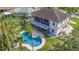 Aerial view of backyard with a kidney-shaped pool, screened patio, palm trees, and lush green grass at 4353 Dewey Dr, New Port Richey, FL 34652