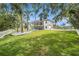 Spacious backyard with lush green grass, tall palm trees, and a kidney-shaped pool with patio at 4353 Dewey Dr, New Port Richey, FL 34652