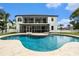 Back of house with screened patio overlooking a kidney-shaped pool in a well-manicured backyard at 4353 Dewey Dr, New Port Richey, FL 34652
