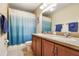 Well-lit bathroom featuring double sinks, tiled floors, and a blue-ombre shower curtain at 5401 Match Point Pl, Lithia, FL 33547