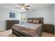 Cozy bedroom features a ceiling fan, dresser, nightstand, and a comfortable bed with warm-toned bedding at 5401 Match Point Pl, Lithia, FL 33547