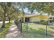 Inviting exterior with a landscaped yard, mature trees, and a black iron fence at 5401 Match Point Pl, Lithia, FL 33547