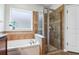 Bathroom featuring a soaking tub with tiled trim work next to a glass enclosed shower with a frosted window at 5401 Match Point Pl, Lithia, FL 33547