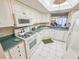 Well-lit kitchen featuring white cabinets, tile backsplash, and a view to the living area at 6060 Shore S Dr # 906, Gulfport, FL 33707