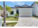 Beautiful light blue, two-story home featuring a two-car garage, manicured lawn, and palm trees at 6534 Simone Shores Cir, Apollo Beach, FL 33572