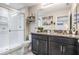 Modern bathroom with a glass enclosed shower, granite countertop, dual sinks, decor and a decorative mirror at 7030 Summer Holly Pl, Riverview, FL 33578