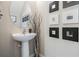 Stylish powder room features pedestal sink, round mirror, and contemporary wall art for an elegant touch at 7030 Summer Holly Pl, Riverview, FL 33578