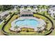 Aerial view of a large, modern community pool and pool house surrounded by lush landscaping at 7030 Summer Holly Pl, Riverview, FL 33578