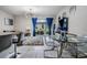 Chic dining area with a glass table and chairs, complemented by blue curtains and natural light at 7030 Summer Holly Pl, Riverview, FL 33578