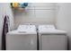 Functional laundry area with white washer and dryer, storage shelf, and ironing board at 7030 Summer Holly Pl, Riverview, FL 33578
