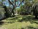 Exterior view of the backyard with green grass, trees and shrubs, with shade covering some of the yard at 7601 Pine Hill Dr, Tampa, FL 33617
