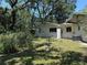 Exterior view of the backyard with green grass, trees, shrubs, utility infrastructure and partially disassembled metal equipment at 7601 Pine Hill Dr, Tampa, FL 33617