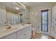Well-lit bathroom with double vanity, tiled floors, and a glass door leading to the outdoor area at 905 Balsamina Dr, Brandon, FL 33510