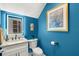 Stylish blue powder room with marble countertop, lighted mirror, and modern fixtures at 10596 Lake Seminole Ter, Seminole, FL 33772