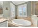 Serene bathroom featuring a luxurious soaking tub with large windows and plantation shutters at 10596 Lake Seminole Ter, Seminole, FL 33772