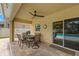 Relaxing covered patio featuring a ceiling fan, outdoor dining set, and access to the pool at 10596 Lake Seminole Ter, Seminole, FL 33772