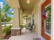 Charming covered front porch with seating area, colorful landscaping, and a decorative front door at 10596 Lake Seminole Ter, Seminole, FL 33772