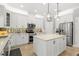 Modern kitchen with white cabinets, a central island, stainless steel appliances, and stylish backsplash at 10596 Lake Seminole Ter, Seminole, FL 33772
