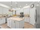 Bright kitchen featuring white cabinets, an island, stainless steel appliances, and mosaic tile backsplash at 10596 Lake Seminole Ter, Seminole, FL 33772