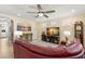 Bright living room featuring a red leather couch, a ceiling fan, and beach-themed artwork at 10596 Lake Seminole Ter, Seminole, FL 33772
