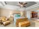 Comfortable main bedroom featuring a tray ceiling, ceiling fan, and a relaxing sitting area at 10596 Lake Seminole Ter, Seminole, FL 33772