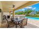 Outdoor patio seating area with an outdoor dining table and clear view of the large in-ground pool at 10596 Lake Seminole Ter, Seminole, FL 33772