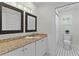 Elegant bathroom with granite countertop, dual decorative framed mirrors, and stylish black and white flooring at 1122 Shipwatch Cir, Tampa, FL 33602
